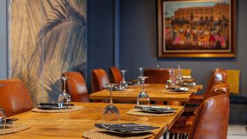 A dining area with wooden tables, leather chairs, and a large abstract painting on the wall.
