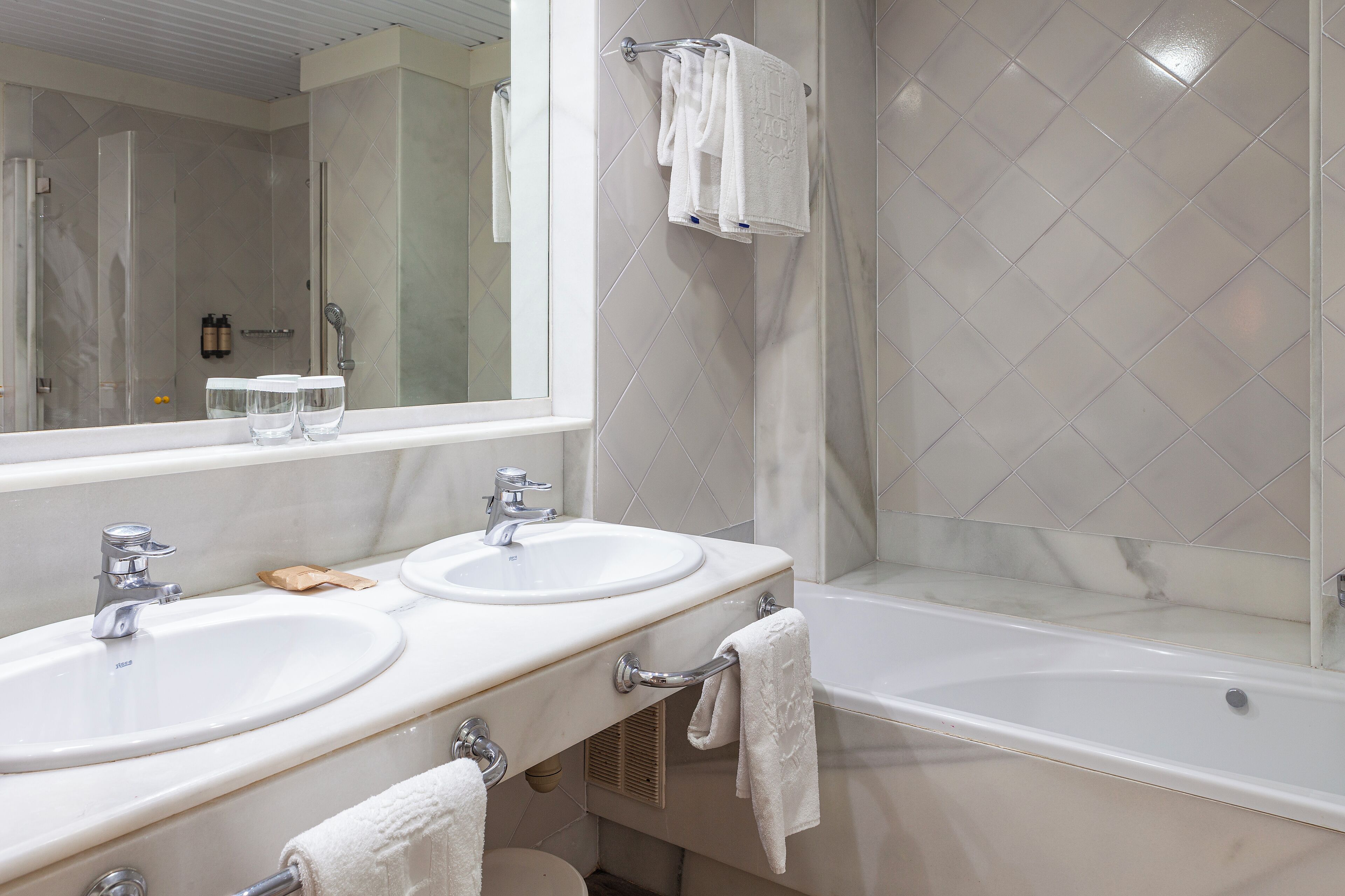 A bathroom with two sinks, a large mirror, and a bathtub.