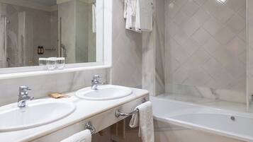 A bathroom with two sinks, a large mirror, and a bathtub.