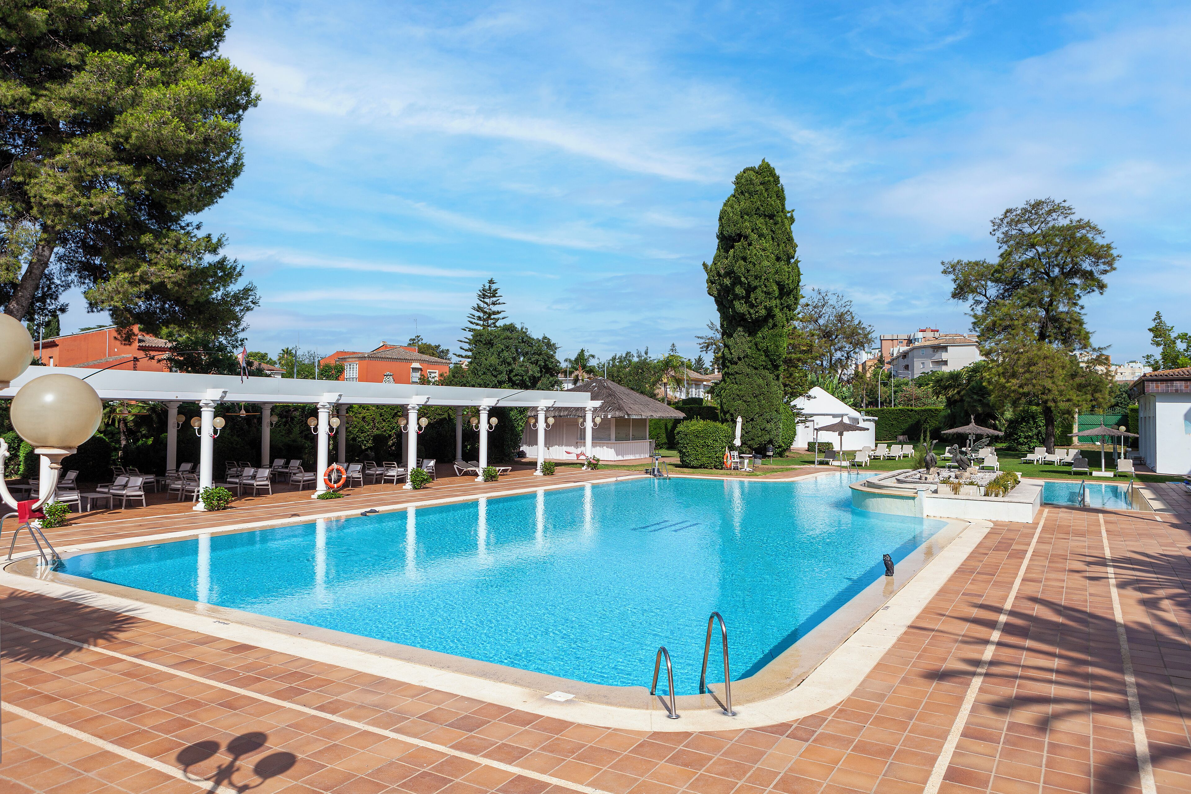 Una grande piscina all'aperto con zona relax coperta e lettini.
