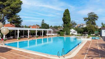 Una grande piscina all'aperto con zona relax coperta e lettini.