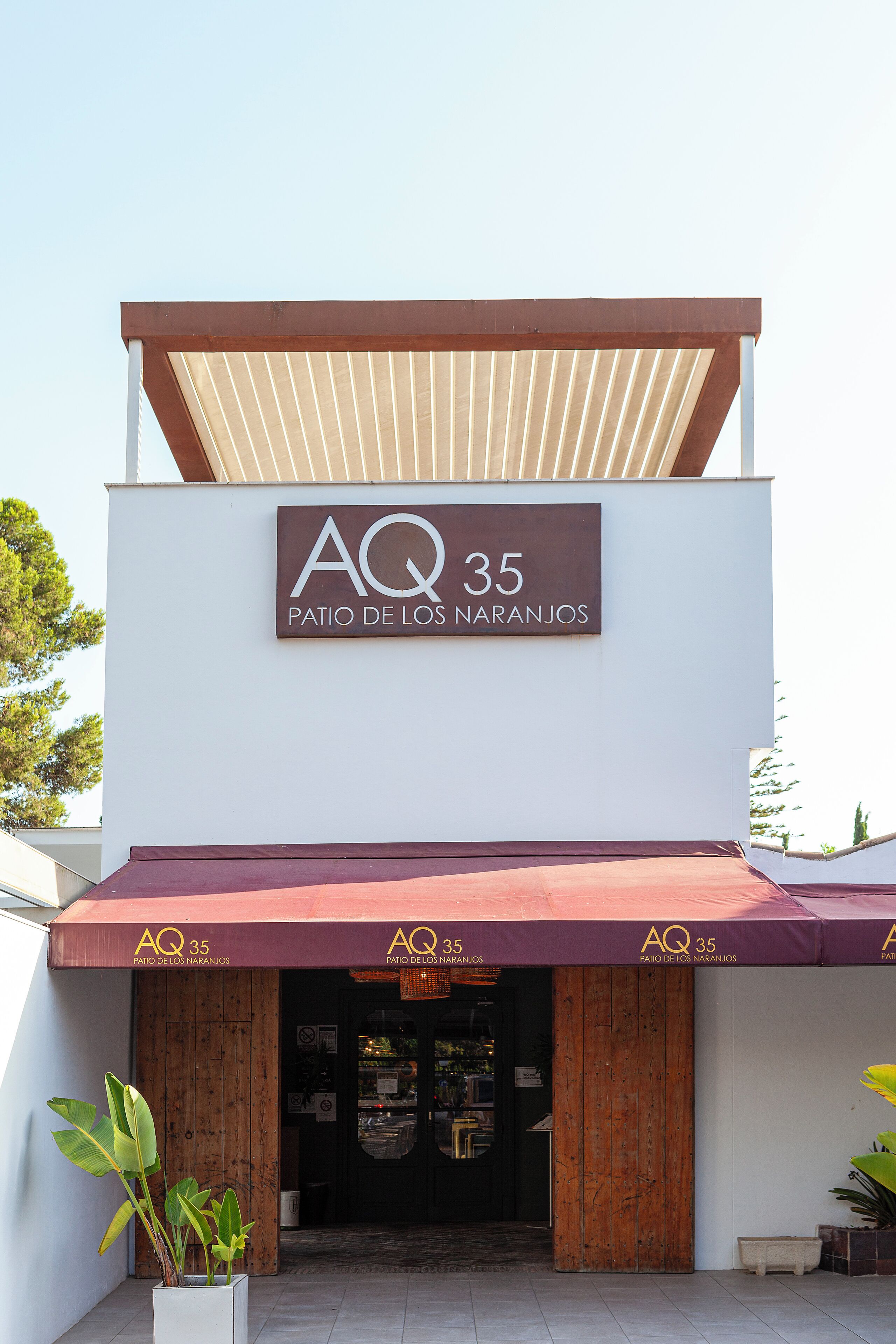 A building with a sign reading 'AQ 35 Patio de los Naranjos' and a covered entrance.