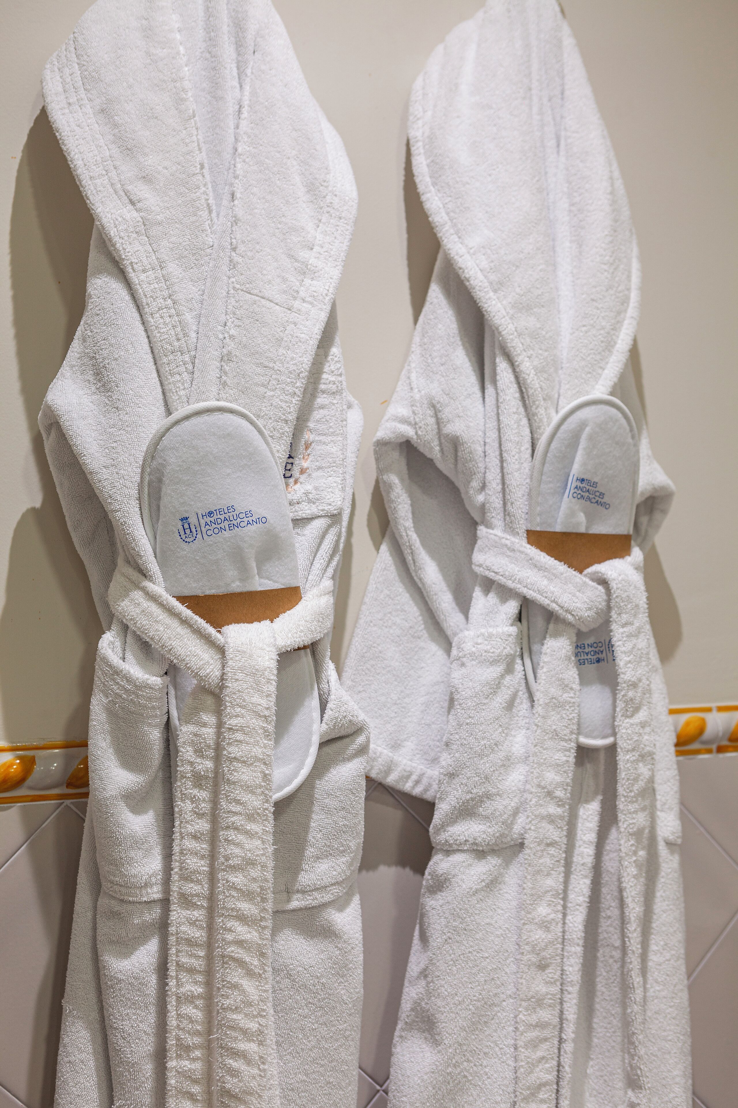 Deux peignoirs blancs sont suspendus à un porte-serviettes dans une salle de bain.