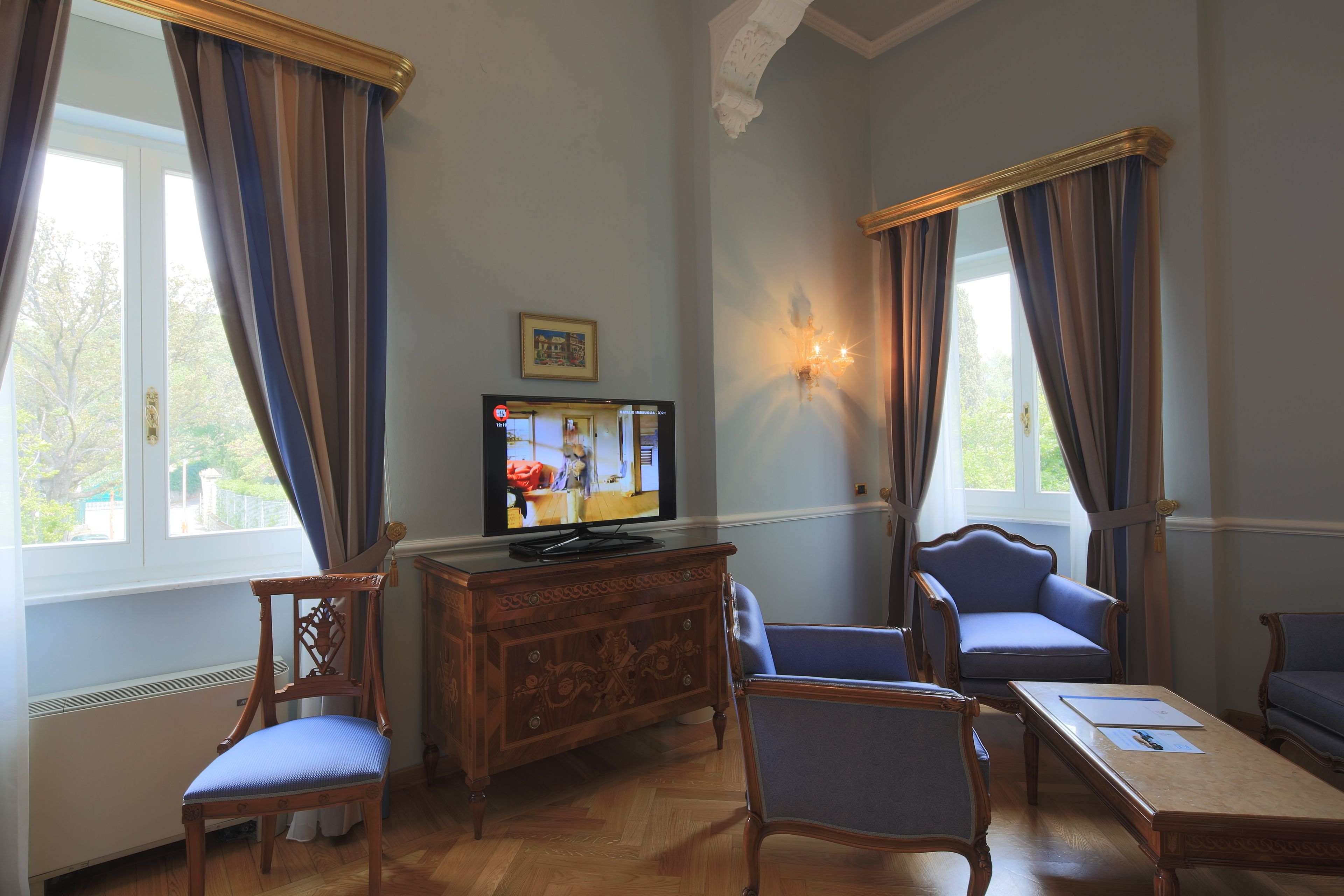 Una habitación con televisión, muebles de madera y cortinas.