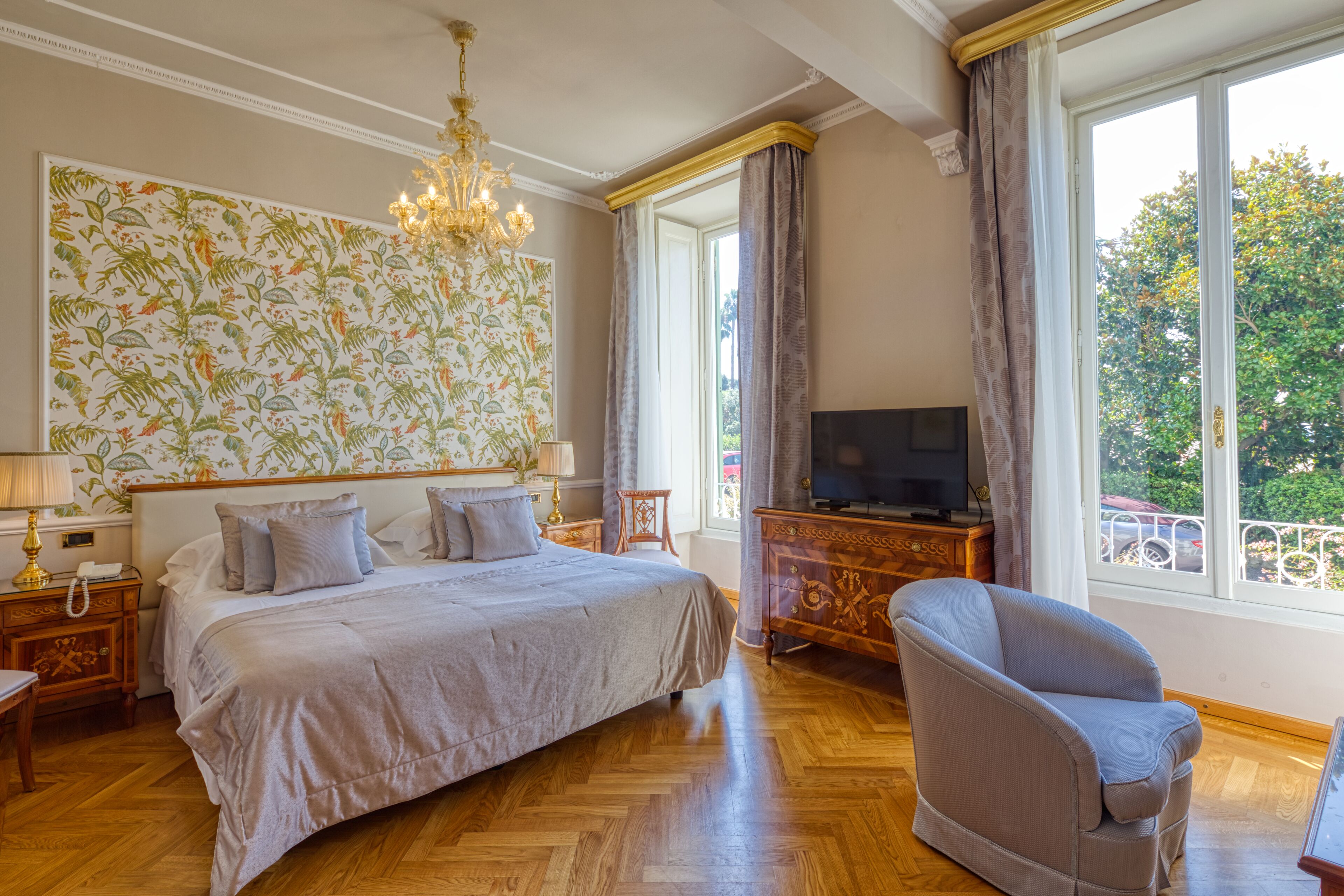 Un'ampia camera da letto con un letto grande, una televisione, una poltrona confortevole e vista sull'esterno grazie a ampie finestre.
