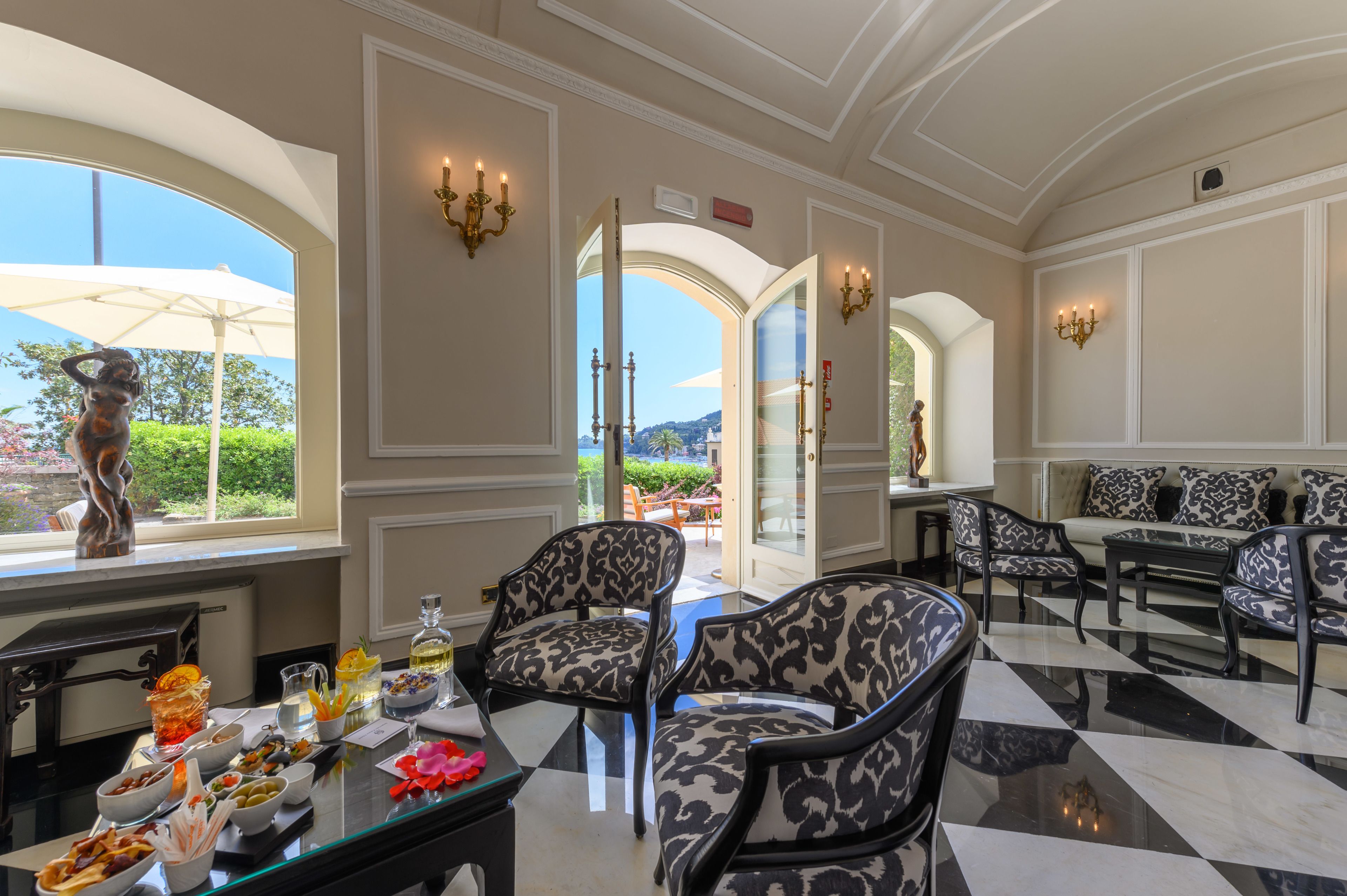 A spacious room with a checkered floor, elegant furniture, and a view through an open door.