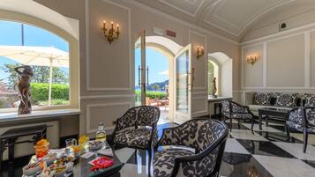 A spacious room with a checkered floor, elegant furniture, and a view through an open door.