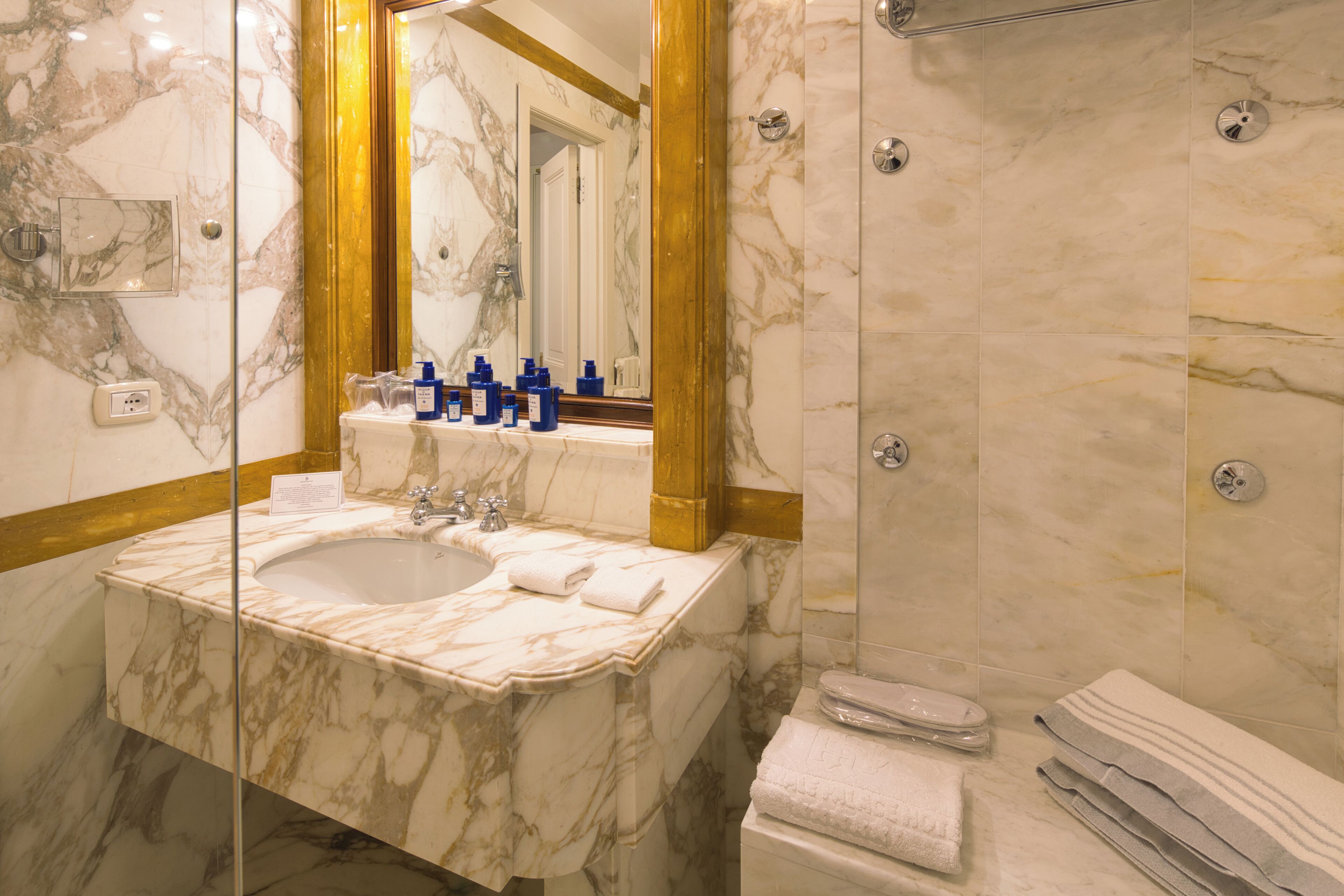 A bathroom with a marble sink, a large mirror, and a shower area.