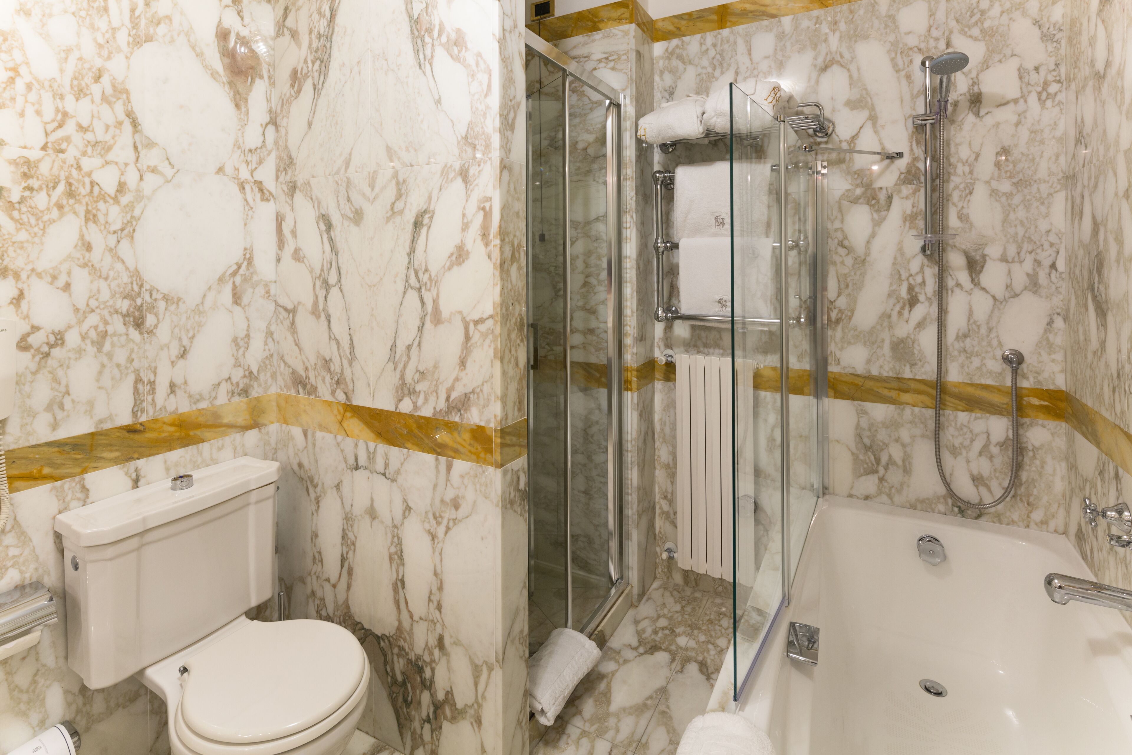 A bathroom with a toilet, a glass-enclosed shower, and a bathtub.