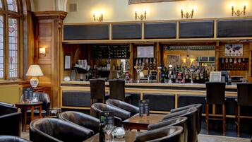 A bar area with leather seating, a bar counter with various bottles, and a menu board.