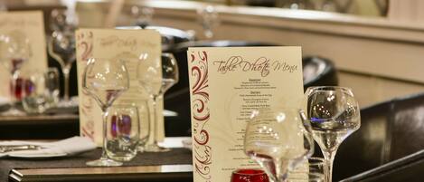 A restaurant setting with tables set for dining, menus, and wine glasses.