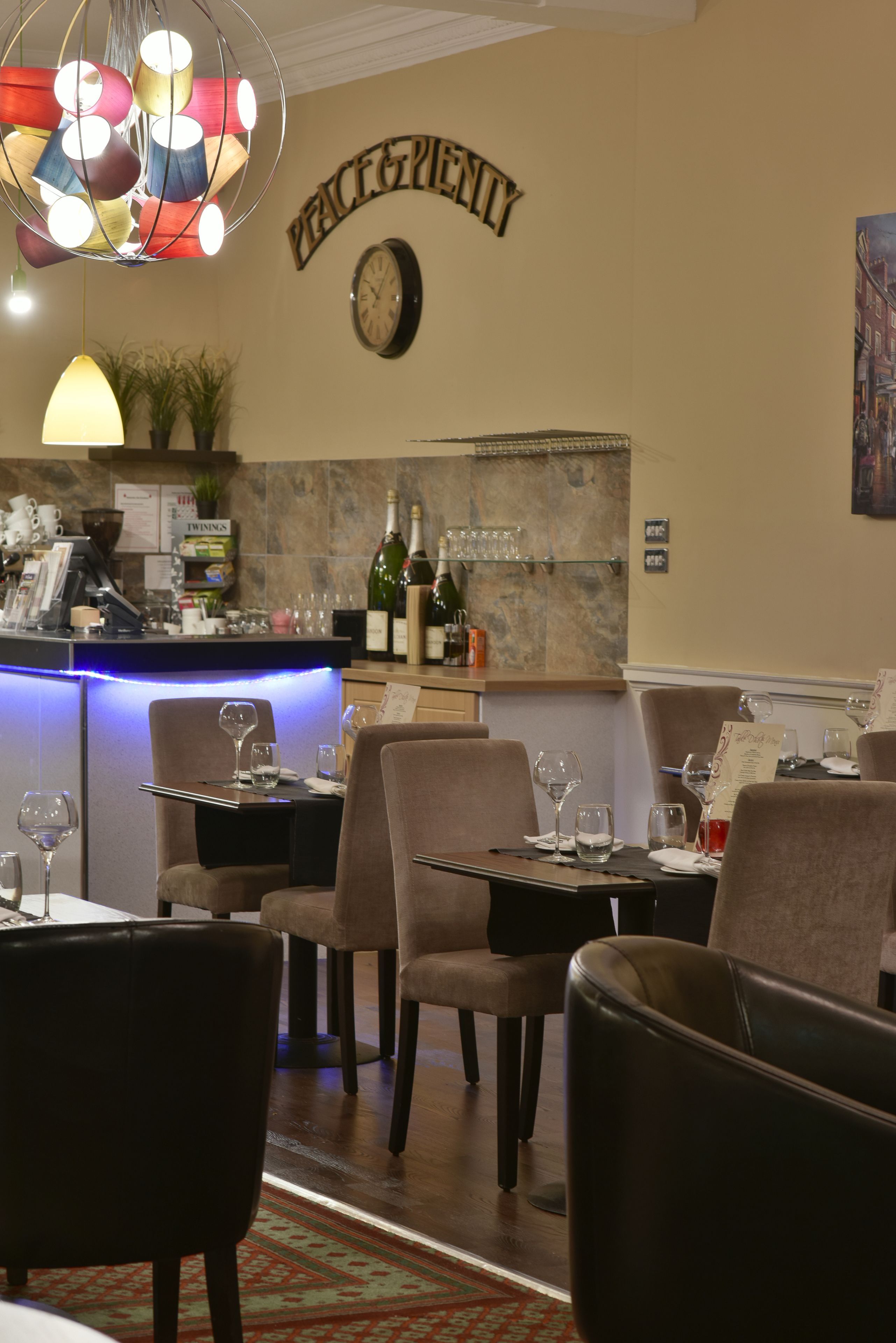 Een restaurant interieur met tafels, stoelen, een bar en een klok aan de muur.