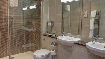 A modern bathroom with a glass-enclosed shower, two sinks, a toilet, and a mirror.
