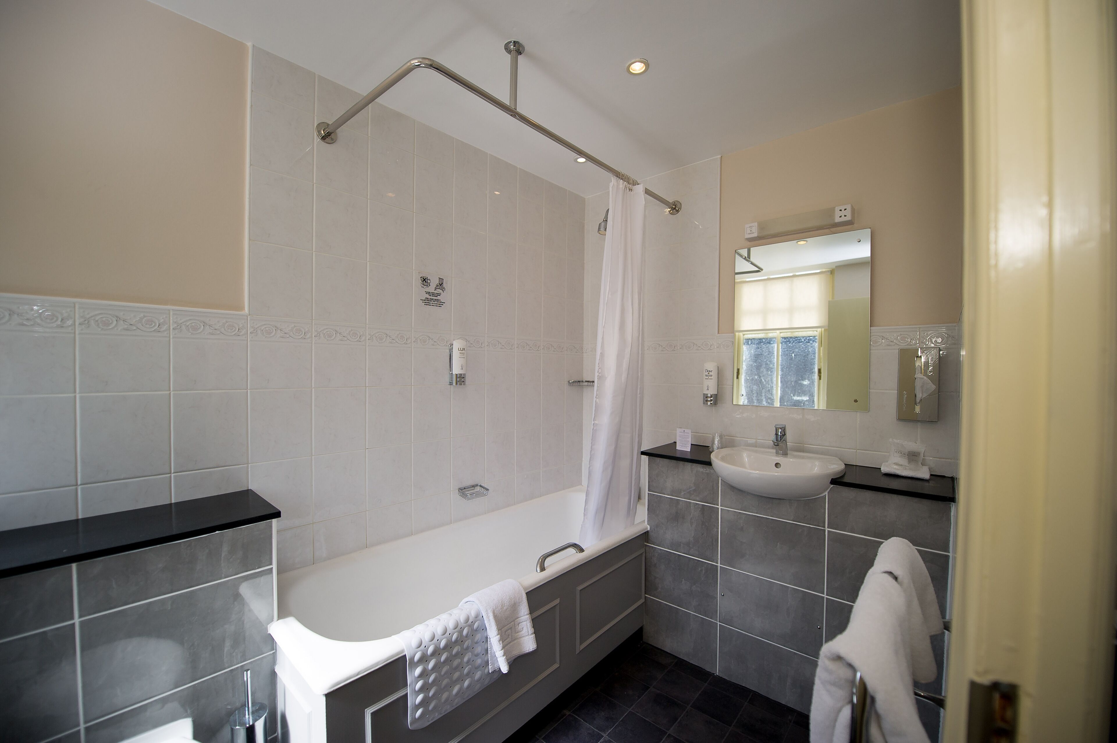 A modern bathroom with a bathtub, a shower, a sink, and a mirror.