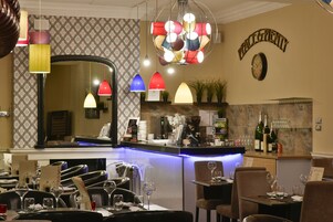 Un interior de restaurante con una zona de bar, varias luces colgantes y un reloj en la pared.