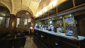 A bar with a long counter, bar stools, and a chalkboard menu.