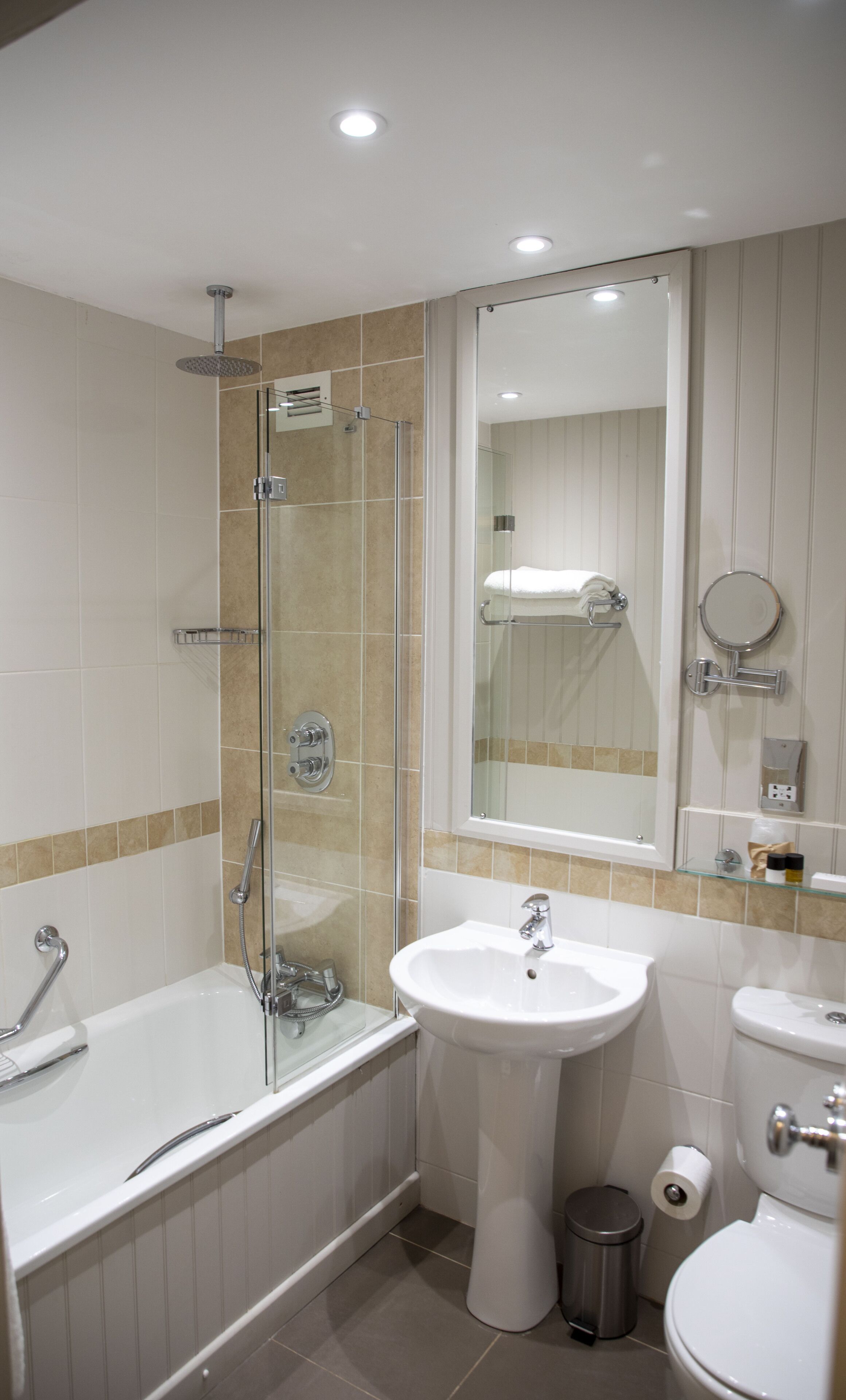 Une salle de bain moderne avec une douche à parois de verre, un lavabo sur colonne, des toilettes et un miroir au-dessus du lavabo.