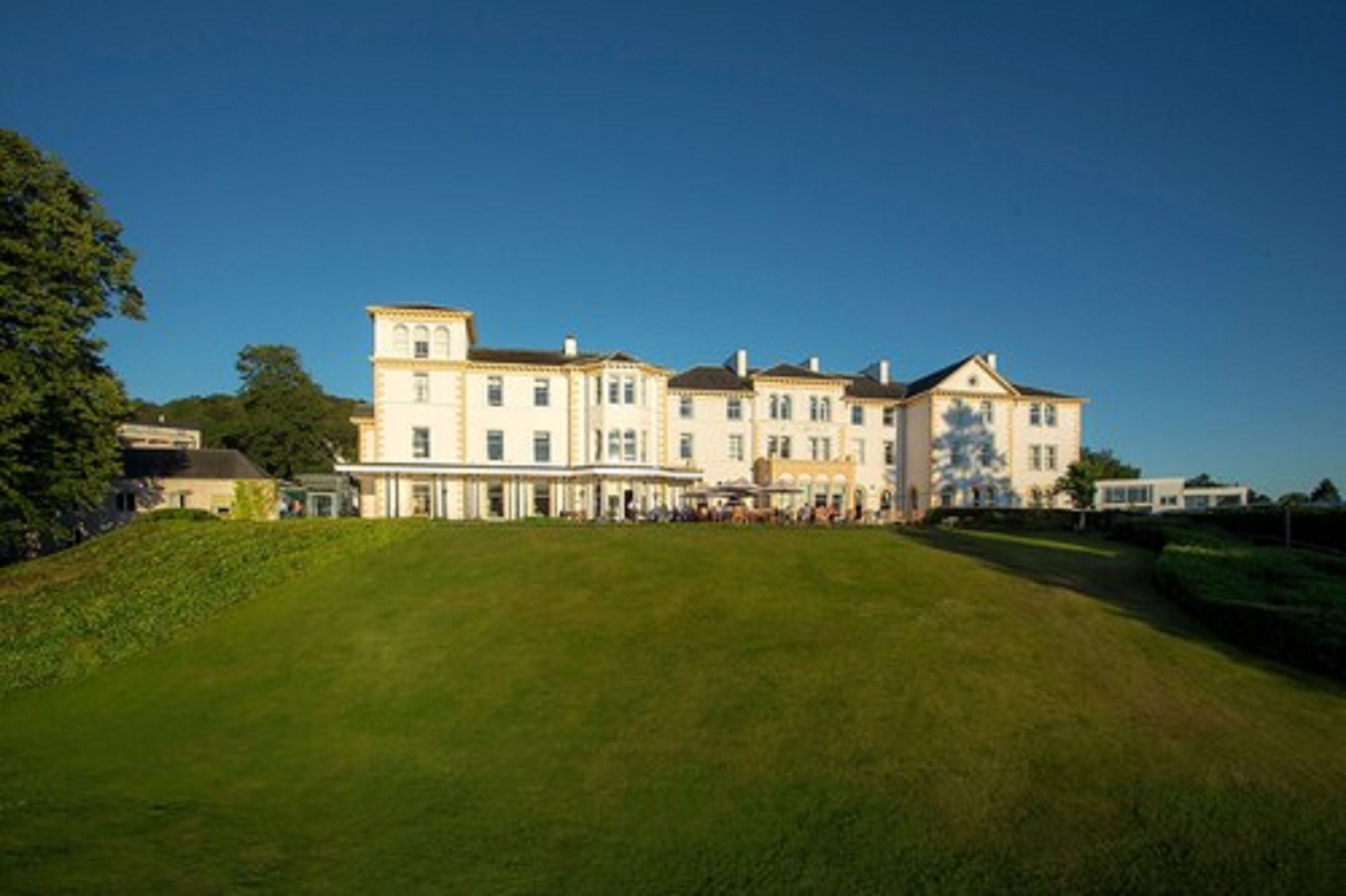 A large, multi-story building with a symmetrical facade, a central entrance, and a well-maintained lawn in front.