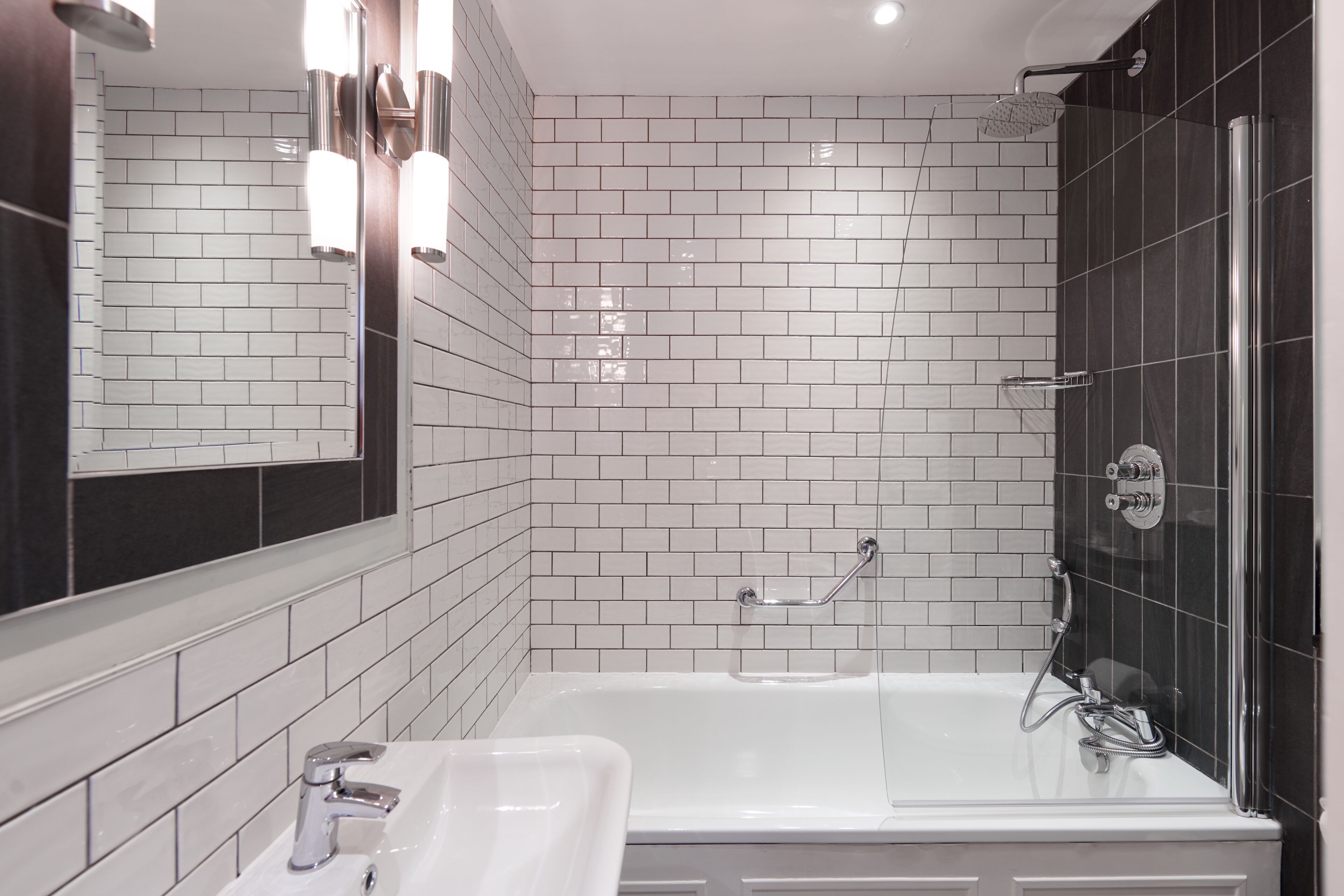 A modern bathroom with a white bathtub, a sink, and a shower area.