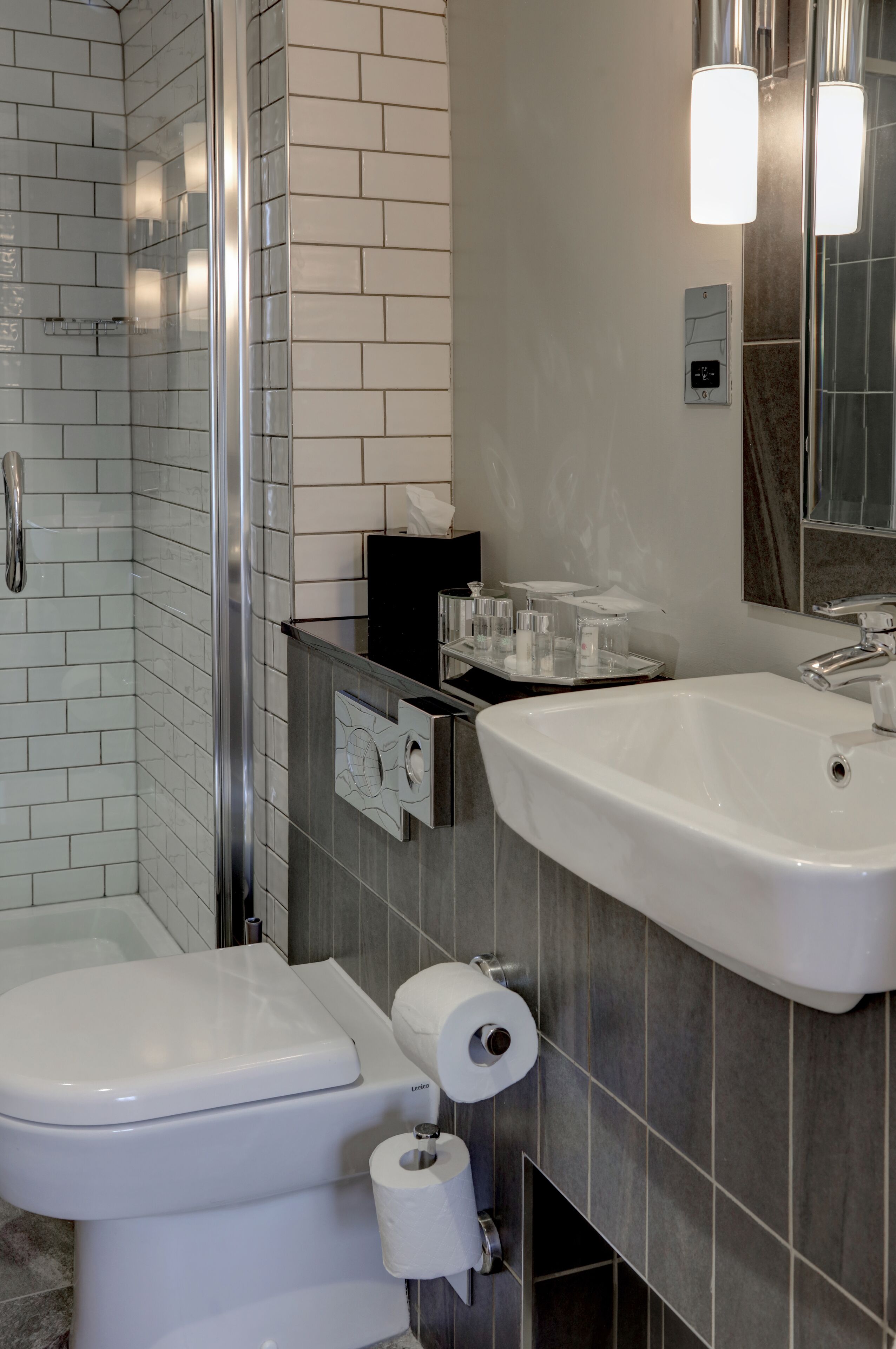 Un baño moderno con cabina de ducha de vidrio, inodoro blanco y lavabo con espejo.