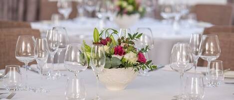 Mesa de comedor dispuesta con varias copas de vino y un centro de mesa con flores.