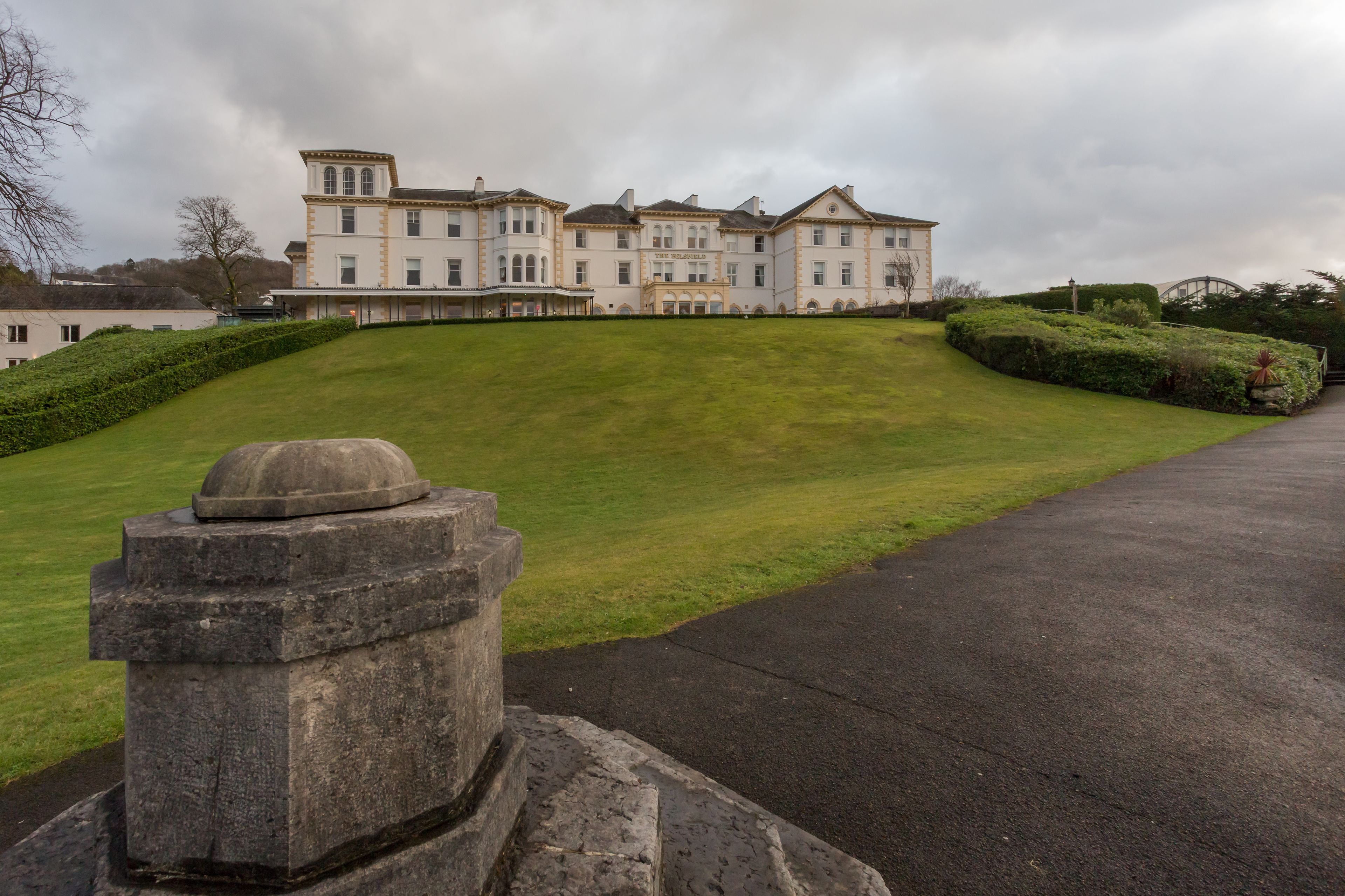 A large, historic building with a symmetrical facade, a central entrance, and a well-maintained lawn.