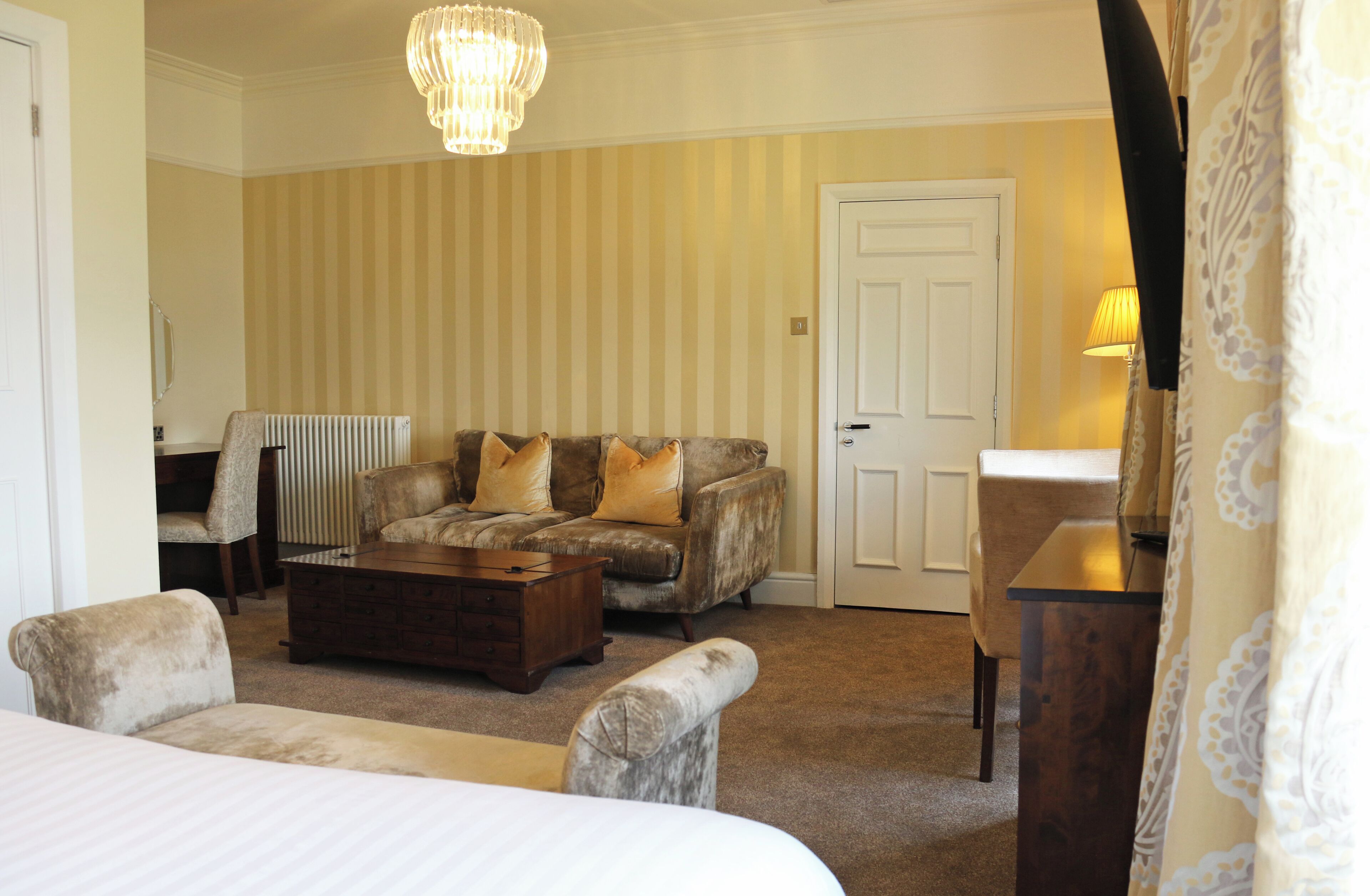Une chambre d’hôtel avec un grand lit, un canapé, une table basse, un fauteuil et une lampe.