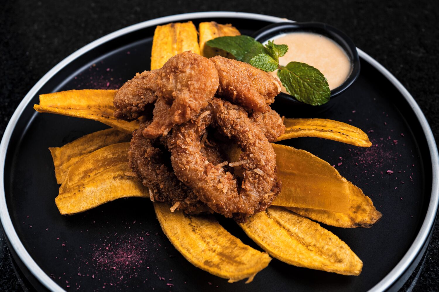 A plate with fried chicken and banana slices.
