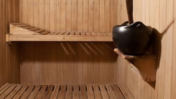Un sauna avec des bancs en bois, une étagère avec un récipient et une caisse remplie de pierres.