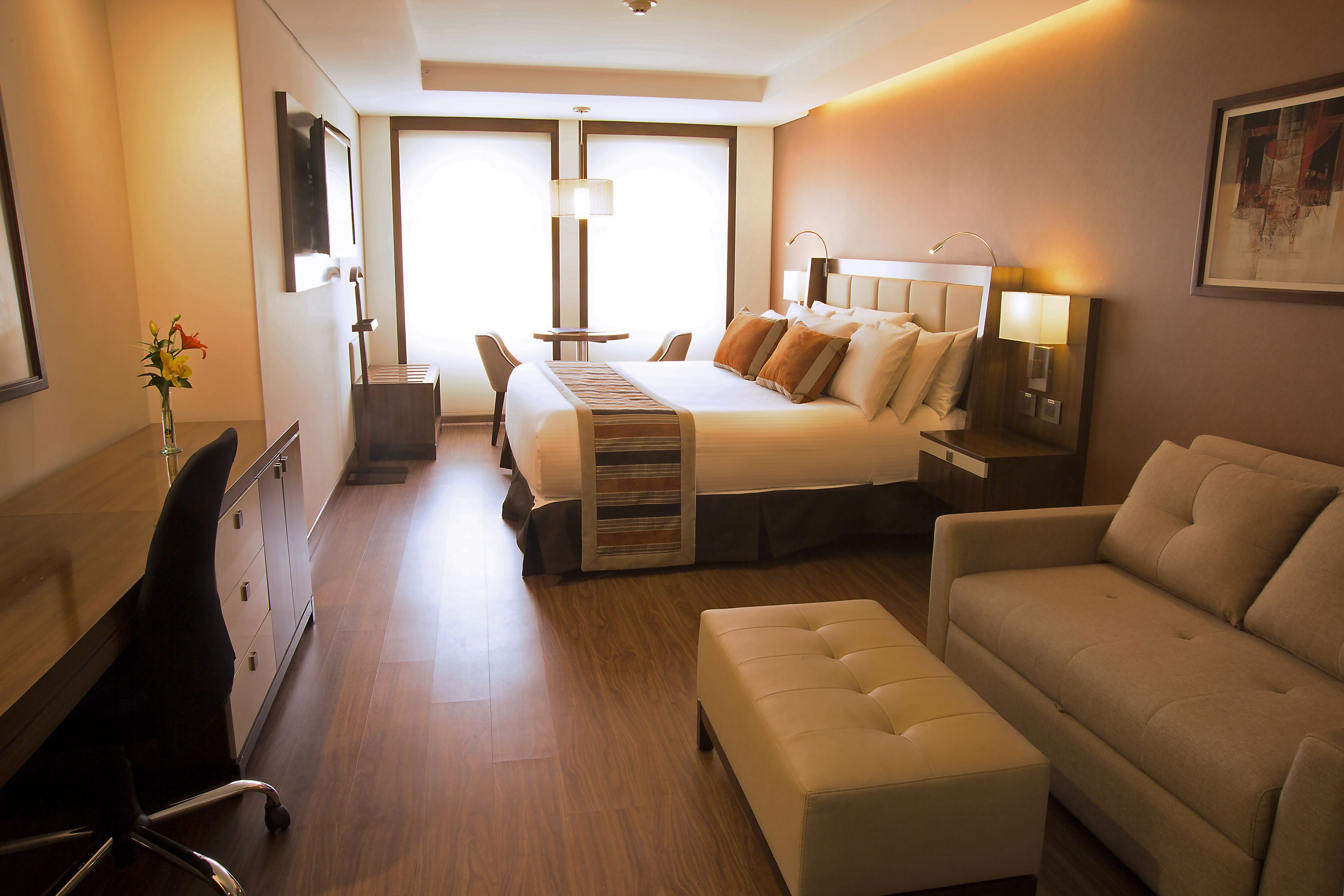 Una habitación de hotel con cama, sofá, escritorio y una silla.