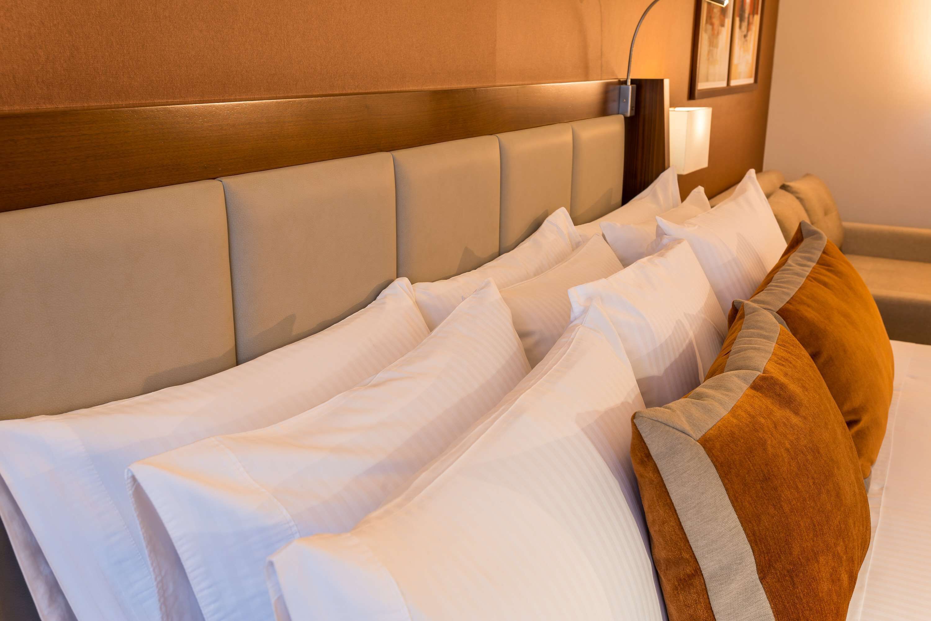 Una cama bien hecha con múltiples almohadas y un cabecero.