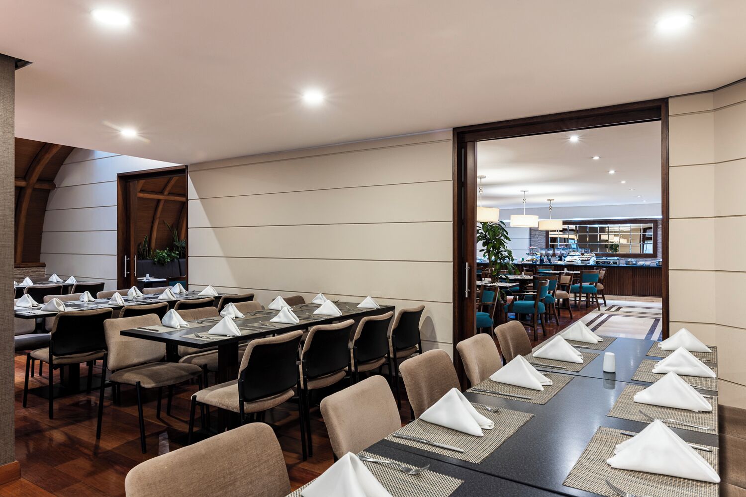 Un salón de conferencias con largas mesas, sillas y vistas a una zona de bar.