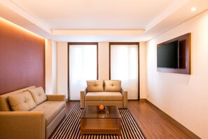 Una sala de estar moderna con un sofá, una mesa de centro y un televisor montado en la pared.