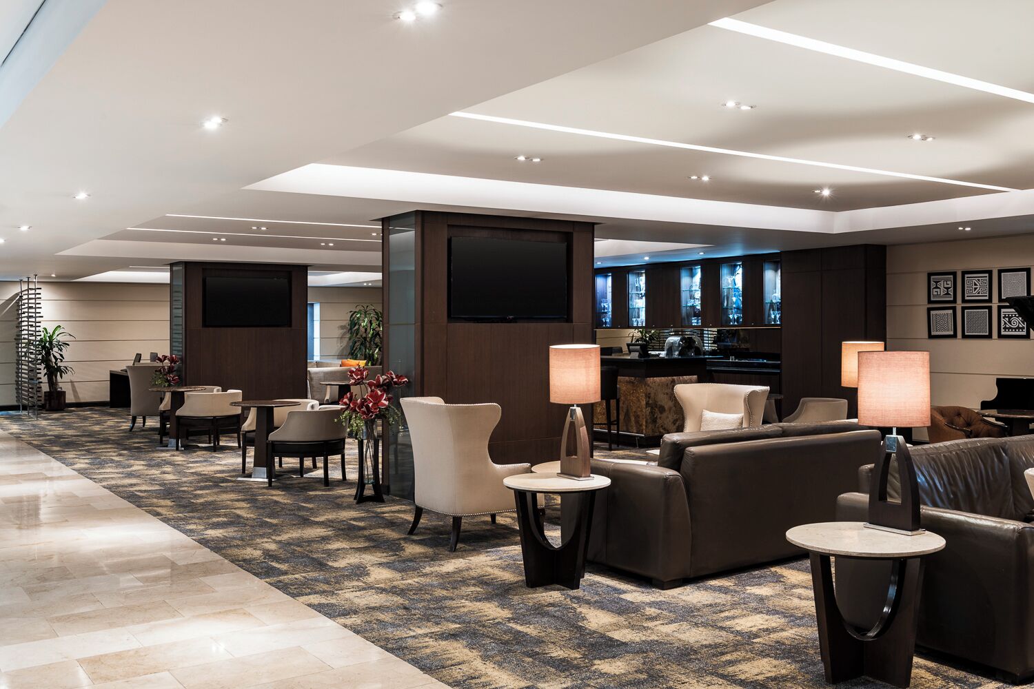 A hotel lobby with a reception desk, seating area, and a bar.