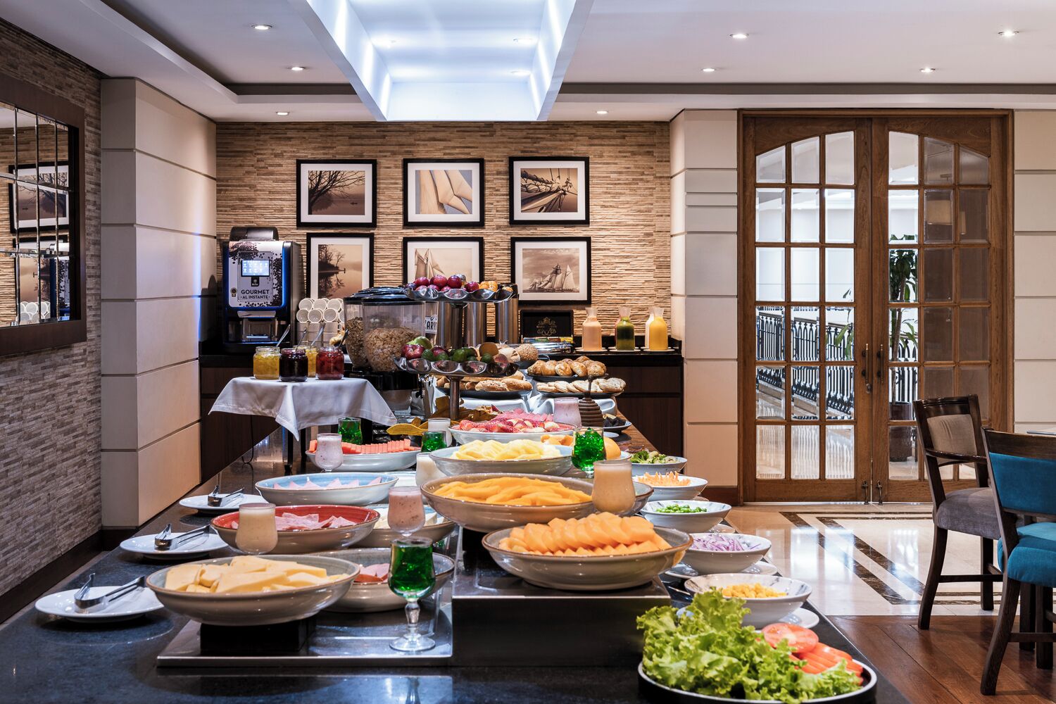 A buffet setup with various food items and a dining area with chairs and a table.