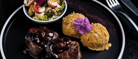 A plate with a steak, a side of mashed potatoes, and a salad.