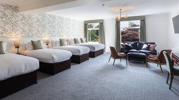 A hotel room with four beds, a sofa, and a chair.