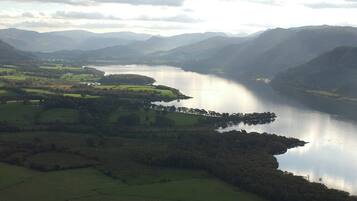 A panoramic view of a lake surrounded by rolling hills and a distant mountain range.