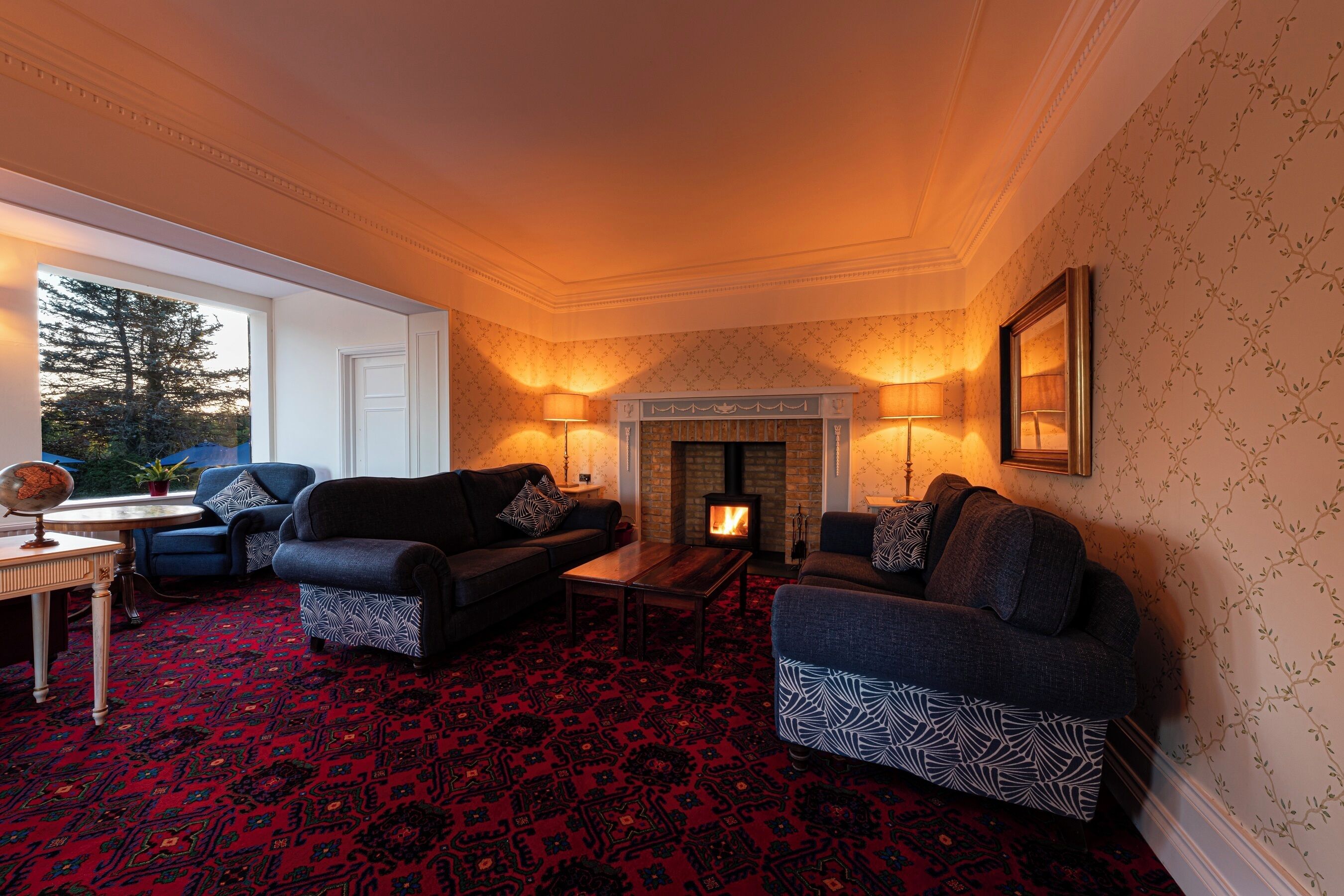 A cozy living room with two sofas, a fireplace, and a patterned carpet.