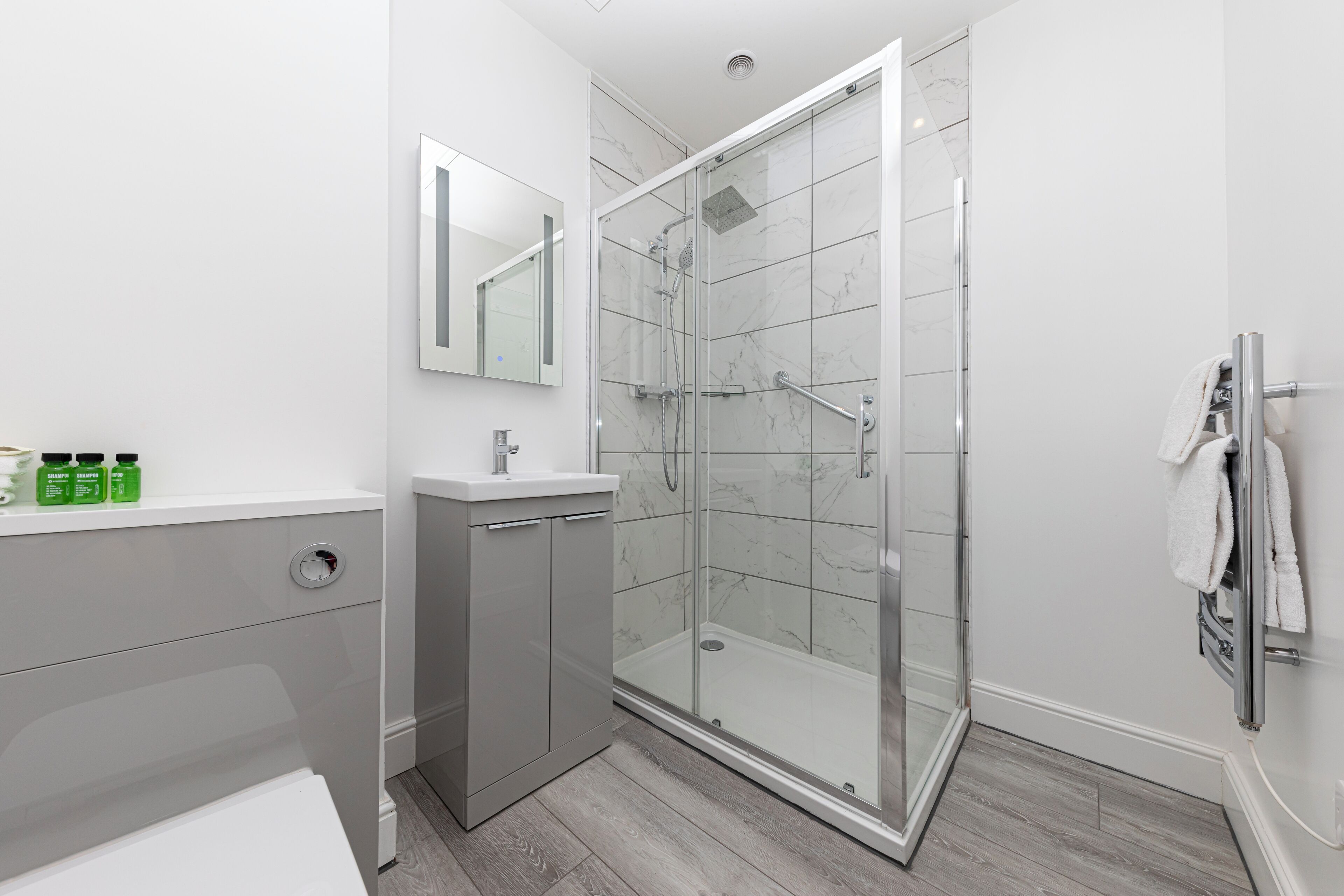 A modern bathroom with a glass-enclosed shower, a white sink, and a mirror above it.