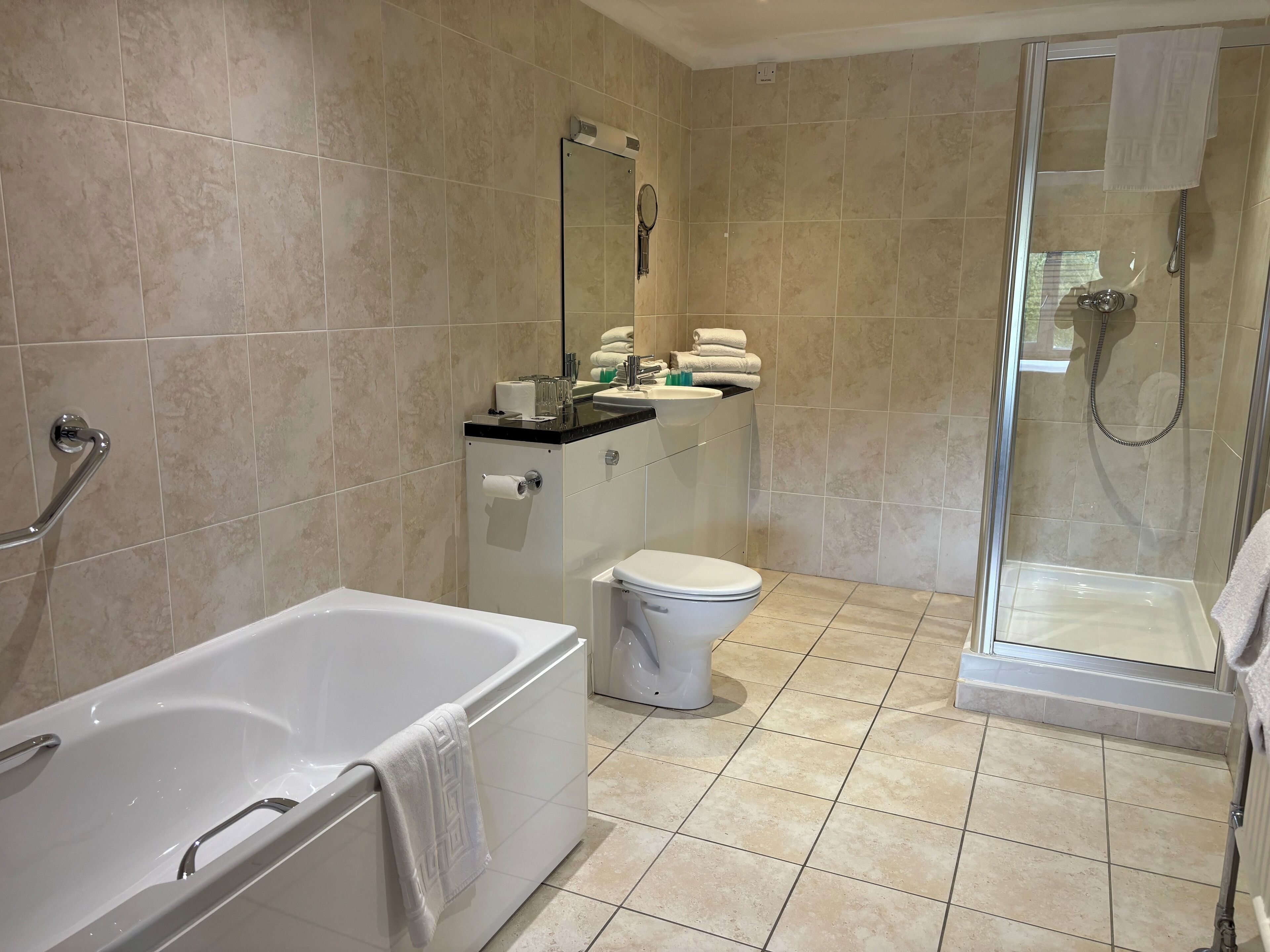 Un baño moderno con bañera, inodoro y ducha con mampara de vidrio.