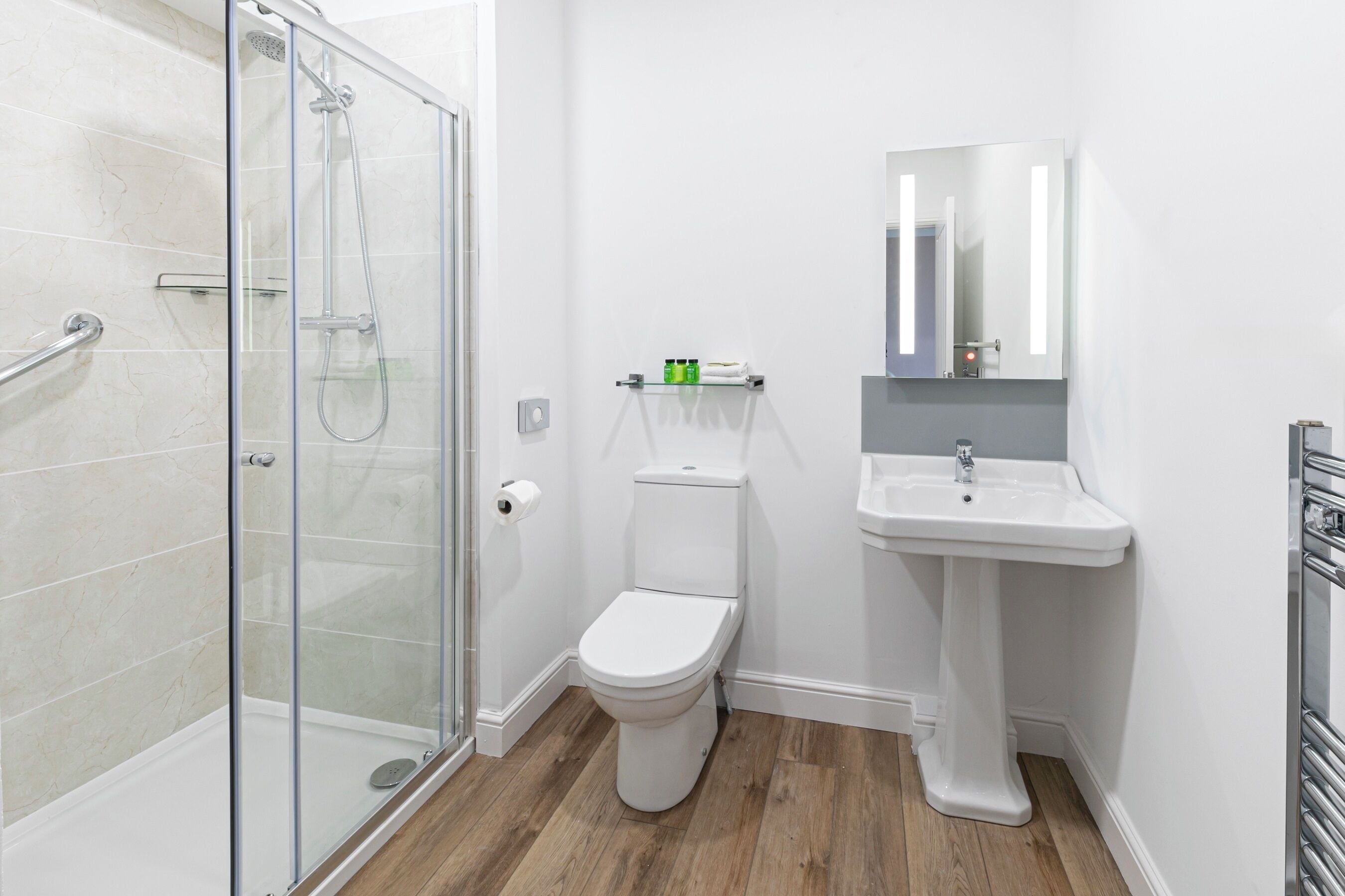 A bathroom with a glass-enclosed shower, a white toilet, and a pedestal sink.