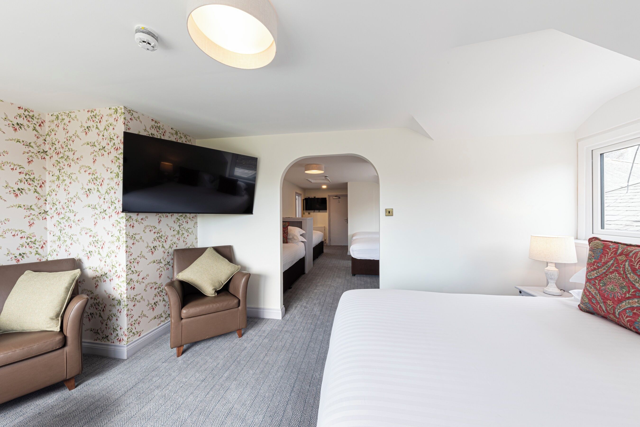 A hotel room with a bed, a TV mounted on the wall, a sofa, and a chair.