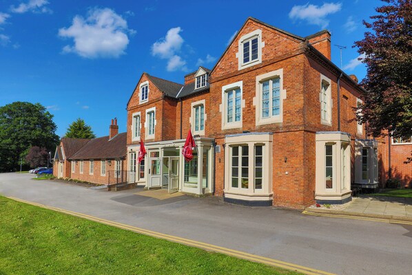 A red brick building with a corner entrance, large windows, and a flag. - Muthu Clumber Park Hotel and Spa (Worksop)