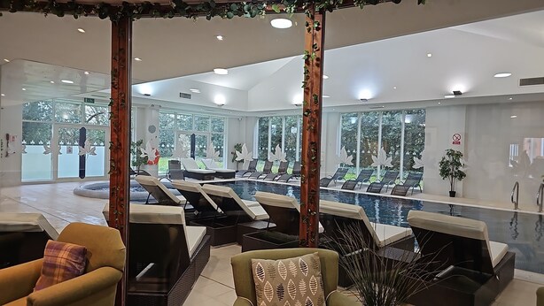 Un área de spa con piscina, sillas de descanso y zona de estar con vistas al exterior.