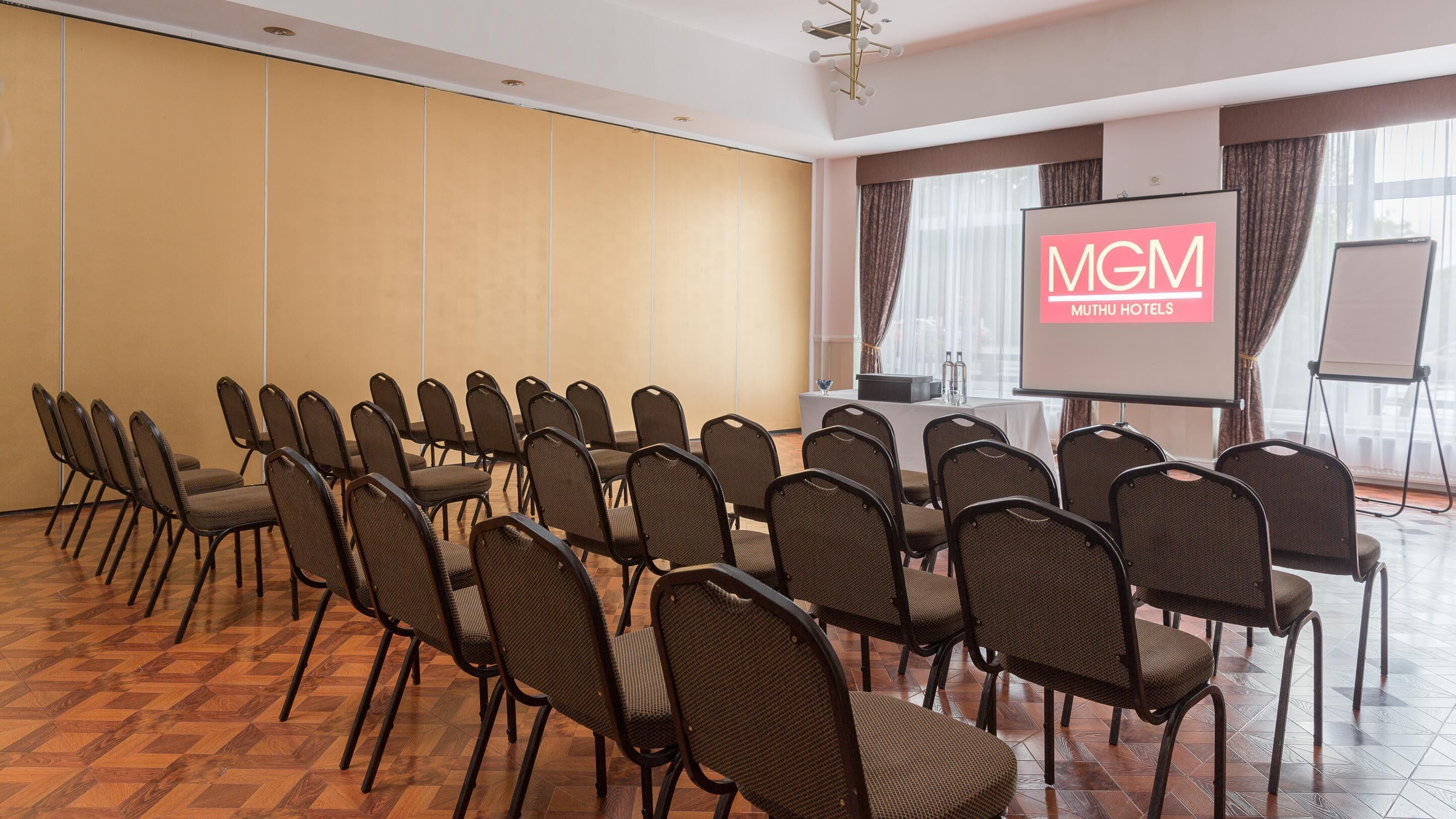A conference room with rows of chairs, a projection screen, and a table with water bottles.