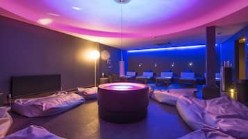 Um quarto com piso circular aquecido, várias poltronas de massagem e uma área de recepção com balcão e cadeiras.