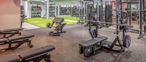 A gym with various exercise equipment, a green exercise area, and a mirrored wall.