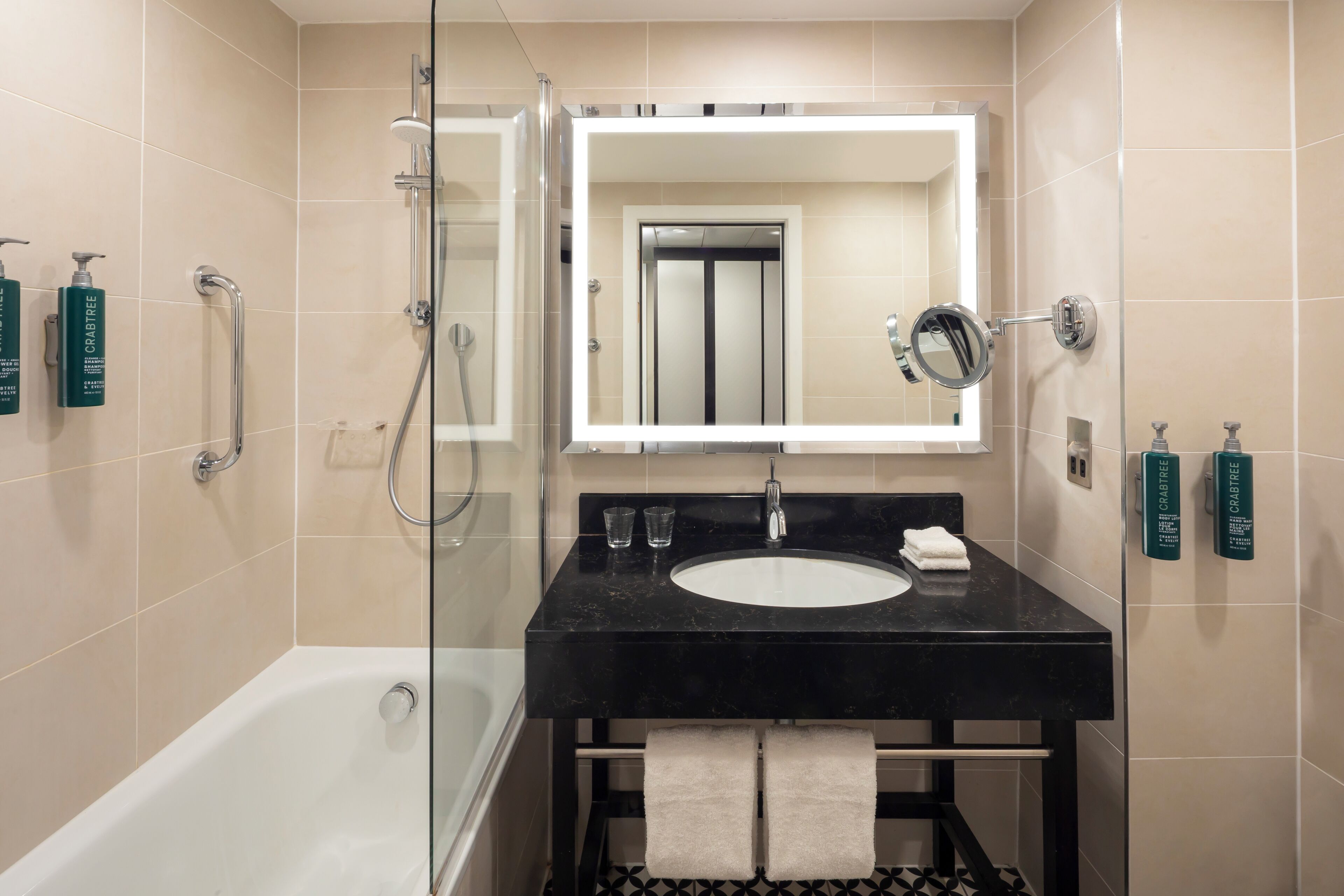 A modern bathroom with a black sink, a glass-enclosed shower, and a large mirror above the sink.