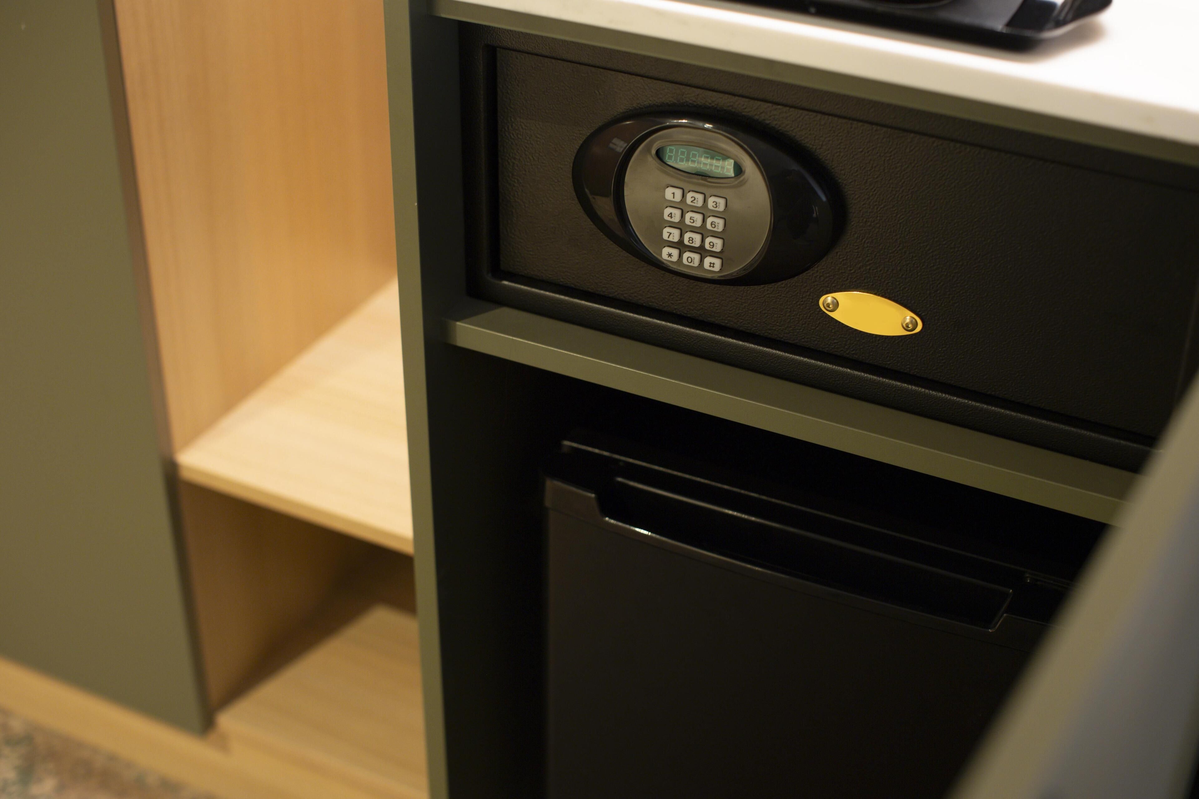A room with a built-in safe, a small shelf, and a black appliance.